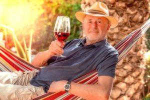 Man in hammock holding a glass of wine