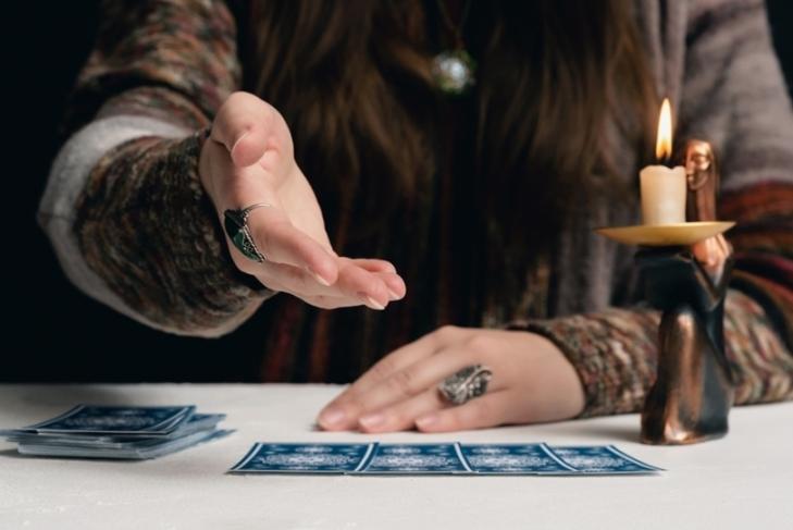 Tarot business being done with Blue Tarot cards on white table with candle