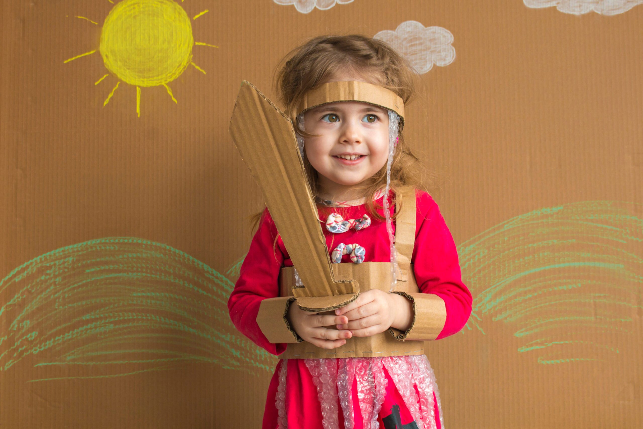 young girl child with cardboard sword smiling, page of swords